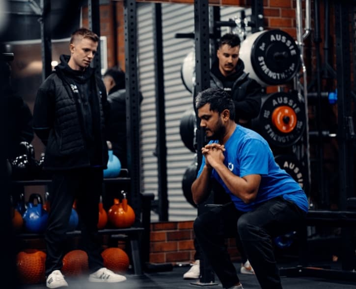 Trainer coaching two clients through a paired session