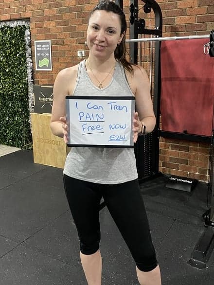 Client holding a whiteboard reading: I can train pain free now